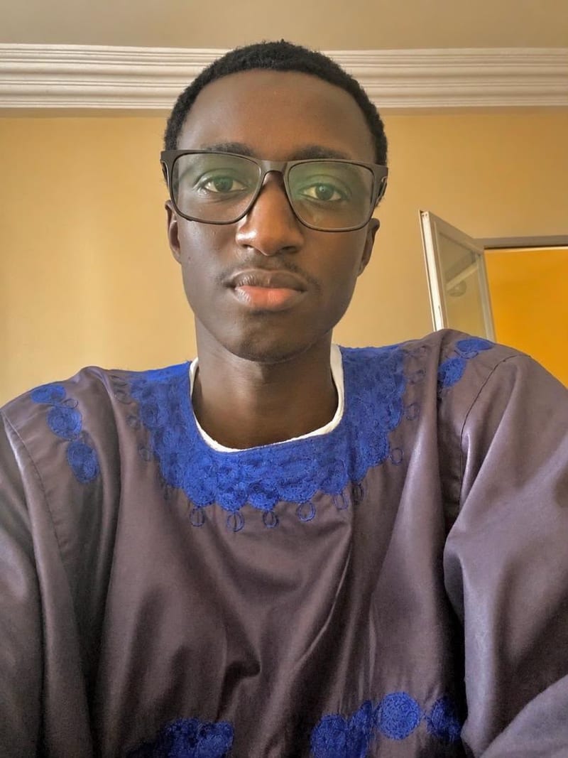 Portrait of Souleymane DIAW wearing a grey boubou with royal-blue embroidery